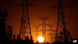 FILE - The sun sets behind high tension power lines on Sept. 23, 2024, in the Porter Ranch section of Los Angeles. The U.S. economy grew at a healthy 2.8% annual rate from July through September, the Commerce Department says.