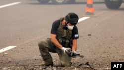 A member of Israeli security forces inspects the impact site of a reported rocket fired from Lebanon, on the Horeshim interchange in central Israel on Oct. 1, 2024.