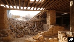 This picture released late Thursday, Aug. 20, 2015, by an Islamic State militant-affiliated website, shows a bulldozer, background, of the IS militants destroying the Saint Elian Monastery near the town of Qaryatain which IS captured in early August.