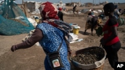 Women carry buckets filled with processed fish on Bargny beach, some 35 kilometers (22 miles) east of Dakar, Senegal, Apr. 25, 2021.