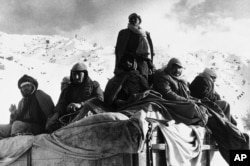 Afghan guerillas huddle together to stay warm while on a road in the mountains of Afghanistan in 1980.