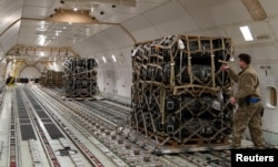 FILE - Senior Airman Cameron Manson inspects cargo netting on palletized ammunition, weapons and other equipment bound for Ukraine at Dover Air Force Base, Delaware, Jan. 24, 2022. (US Air Force photo/Roland Balik/Handout via Reuters)
