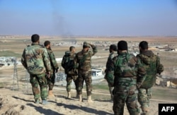 Syrian pro-government fighters look at smoke rising on the horizon following government air strikes on the Tal Sharba area, on the outskirts of Aleppo, after they seized the area from Islamic State (IS) group jihadists on Dec. 27, 2015.
