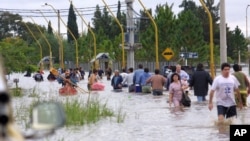 FILE - People walk in the water as they leave the flooded area of Santa Fe, some 390 kilometers, (250 miles) northwest of Buenos Aires, Argentina, April 30, 2003.