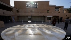 People stand during a moment of silence to honor 400,000 US COVID-19 victims outside the Cathedral of Our Lady of Angels in Los Angeles, Jan. 19, 2021. 