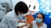 A healthcare worker administers a COVID-19 vaccine to an Israeli woman at Clalit Health Services, in the coastal city of Tel Aviv, Jan. 3, 2021.