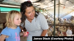 Farmer Ruth Mylroie witnesses a chicken laying an egg with a young visitor during a school tour of New Harmony Farm.