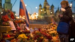 FILE - A woman lays a bunch of flowers where Boris Nemtsov was gunned down on Feb. 27, 2015.