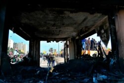 FILE - Protesters are seen through broken windows of a burned checkpoint in front of the U.S. embassy in Baghdad, Iraq, Jan. 1, 2020.