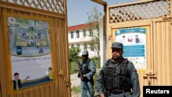 Afghan policemen stand guard at a gate of a voter registration center for the upcoming parliamentary and district council elections in Kabul, Afghanistan, April 23, 2018.