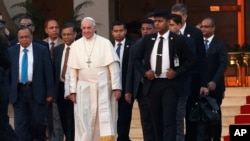Pope Francis is flanked by Bangladeshi officials and security guards as he walks to the airplane before his departure from the airport in Dhaka, Bangladesh, Saturday, Dec. 2, 2017.