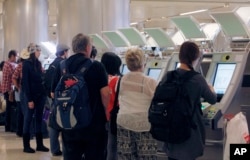 FILE - Passengers arriving from abroad at Los Angeles International Airport use new automated passport kiosks.