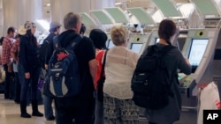FILE - Passengers arriving from abroad at Los Angeles International Airport use new automated passport kiosks.