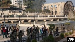 Syrian anti-government fighters gather among civilians near of one of Hama's water wheels, or norias, after forces captured the city on Dec. 6, 2024.