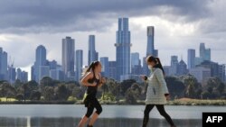 People exercise in front the city skyline in Melbourne on August 29, 2021, as authorites announced the extension of an ongoing coronavirus lockdown in Australia's second-biggest city. (Photo by William WEST / AFP)