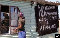 FILE - A man replaces a broken window at a tavern in Philippi township, on the outskirts of Cape Town, South Africa.