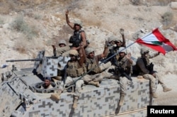 FILE - Lebanese army soldiers gesture as they sit on their military vehicles in the town of Ras Baalbek, Lebanon, Aug. 21, 2017.