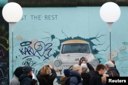 People stroll past and take pictures next to the installation 'Lichtgrenze' (Border of Light) along the East Side Gallery, the largest remaining part of the former Berlin Wall, Berlin, Germany, Nov. 9, 2014.