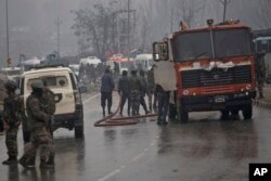Indian firemen spray water on a road to wash away blood after an explosion in Pampore, Indian-controlled Kashmir, Thursday, Feb. 14, 2019.