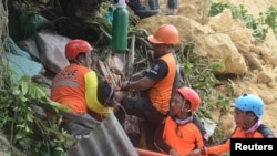 Rescuers pull out a survivor from rubble after a landslide in the city of Naga, Cebu island, Philippines, Sept. 20, 2018.
