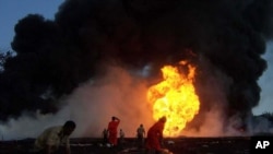 Para petugas pemadam kebakaran mencoba memadamkan api di sumur minyak yang terbakar milik Oil India, di Dikom, negara bagian Assam, India, 9 Juni 2020.
