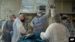 Medical workers in protective clothing treat a COVID-19 patient at the intensive care unit in the public Oceanico hospital, in Niteroi, Brazil, Dec. 11, 2020.