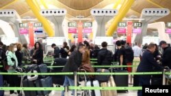 FILE PHOTO: Passengers wait for checking-in before boarding their flights to the U.S. at Madrid's Adolfo Suarez Barajas airport