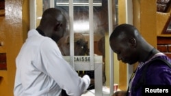 Men buy cinema tickets at the entrance at Cine Burkina during the Panafrican Film and Television Festival (FESPACO) in Ouagadougou, Burkina Faso, March 3, 2017.