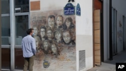 A man looks at a painting by French street artist Christian Guemy, aka "C215," in Paris on Sept. 2, 2020, in tribute to the members of the satirical newspaper Charlie Hebdo attack by jihadist gunmen in January 2015.