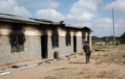 FILE - A member of Kenya's security forces walks past a damaged police post after an attack by al-Shabab extremists from Somalia, in the settlement of Kamuthe in Garissa county, Kenya, Jan. 13, 2020.