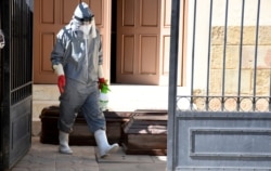 A health worker disinfects empty coffins that will be used to take the bodies of recently deceased residents of the San Jose nursing home in Cochabamba, Bolivia, July 16, 2020.