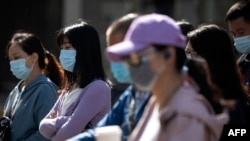 Orang-orang yang memakai masker di tengah kekhawatiran virus corona, di sebuah jalan di Beijing pada 13 Mei 2020. (Foto: AFP/Noel Celis)