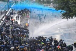 Pro-democracy protesters react as police fire water cannons outside the government headquarters in Hong Kong, Sept. 15, 2019.