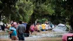 Residents walk past inundated vehicles in the flooded streets of Planeta, Honduras, Nov. 6, 2020, in the aftermath of Hurricane Eta. 