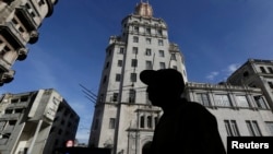 FILE - A man walks in front of the headquarters of Cuba's state-run telecommunications provider ETECSA in Havana.