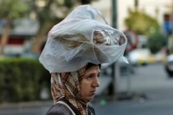 FILE - A woman carries bread on her head while she crosses a street in Damascus, July 24, 2019. After nearly a decade of war, Syria is crumbling under the weight of sanctions, government coruption and other problems.