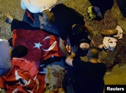 An injured woman draped in a Turkish flag is checked by others near military headquarters in Ankara, Turkey, July 16, 2016.