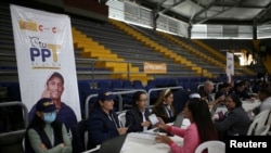 FILE - Colombian Migration employees work during a day of Temporary Protection Permit deliveries organized by Colombian Migration at the Sports Palace in Bogota, Colombia, Sept. 1, 2023.