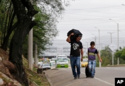 En esta foto del 28 de junio de 2018, el padre venezolano Darwin Zapata camina con su hijo de 12 años por una carretera en Cúcuta, Colombia, mientras se dirigen a Perú.