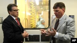 FILE - Tom Geisbert, right, a professor of Microbiology and Immunology at the University of Texas Medical Branch, explains to Texas Gov. Rick Perry the work researchers are conducting in a Bio Safety Level 4 lab in the Galveston National Laboratory, Oct.