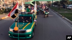 Iraqi security forces raise Iraqi national flags in a parade marking the year anniversary of the defeat of the Islamic State group in Iraq in Tahrir Square, in central Baghdad, Monday, Dec. 10, 2018. (AP Photo/Ali Abdul Hassan)