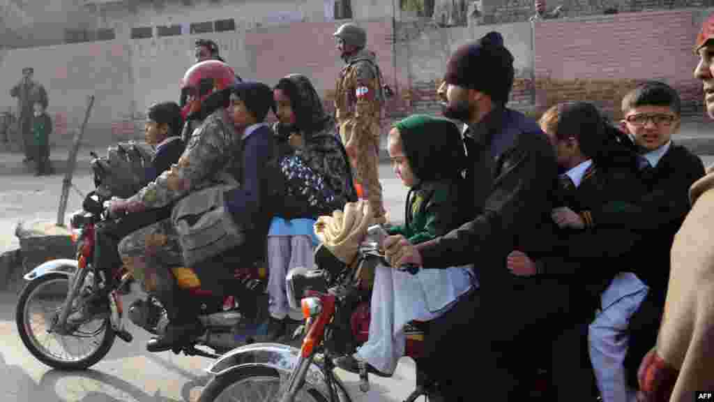 Pakistani parents leave with their children near the site of an attack by Taliban gunmen on a school in Peshawar, Dec. 16, 2014. 