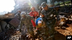 In a disaster drill, soldiers from Chinese PLA Southern Theater Command Army and the U.S. Army Pacific carry an injured man from a mock earthquake-collapsed building as they conducting a joint rescue operation in the U.S.-China Disaster Management Exchange drill at a training base in Kunming, China, Nov. 18, 2016.
