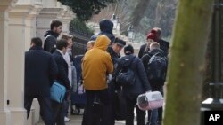 Orang-orang dengan membawa koper meninggalkan Kedutaan Besar Rusia di London, Selasa, 20 Maret 2018. Puluhan diplomat Rusia diperintahkan untuk meninggalkan Inggris setelah serangan racun saraf terhadap mantan mata-mata Rusia di wilayah Inggris.