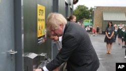 Le Premier ministre britannique Boris Johnson se lave les mains dans la cour de récréation lors d'une visite à l'école primaire de Bovingdon à Bovingdon, Hemel Hempstead, Angleterre, vendredi 19 juin 2020. (Steve Parsons / Pool via AP)