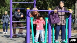 资料照：北京天坛公园里的老年人和他们的独生子女的孙辈在锻炼身体。（2011年10月25日）