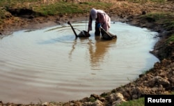 FILE - A Cambodian farmer collects water during the dry season in Kandal province, on the outskirts of Phnom Penh, March 18, 2010.