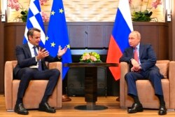 Russian President Vladimir Putin, right, and Greek Prime Minister Kyriakos Mitsotakis talk during their meeting at Bocharov Ruchei residence in the Black Sea resort of Sochi, Russia, Dec. 8, 2021.