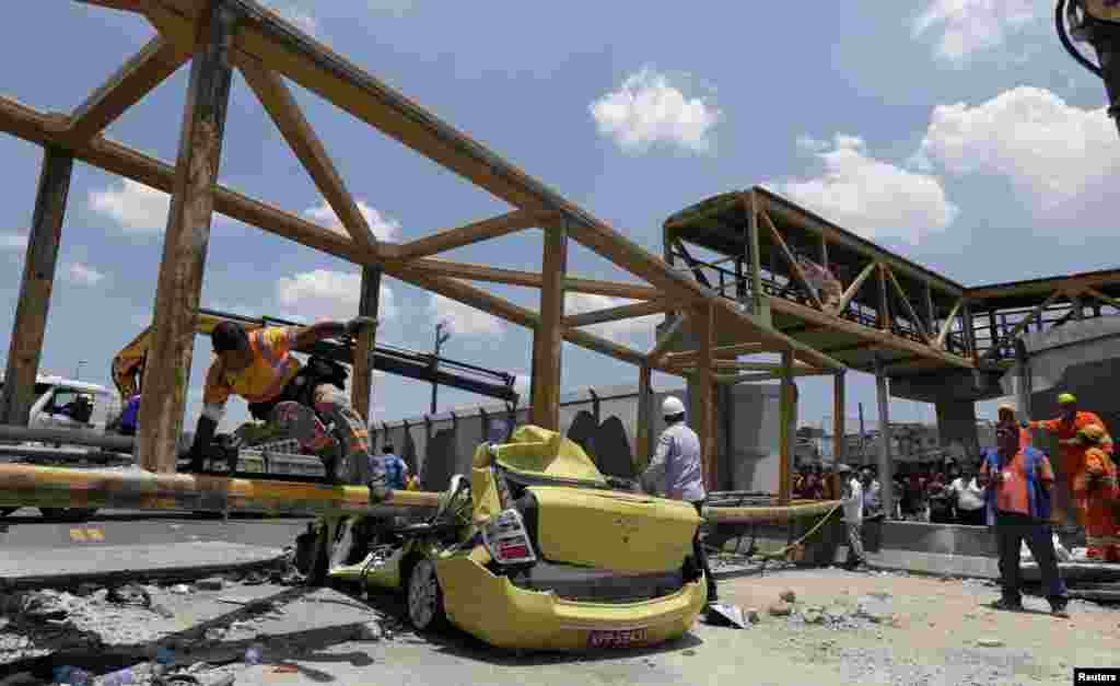 Seorang pekerja melompati sebuah taksi yang rusak berat dalam kecelakaan di dekat jembatan pejalan kaki di Rio de Janeiro, Brazil.