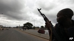 A pro-Ouattara fighter from a group which calls itself the "invisible commandos" patrols a street in northern Abidjan's Abobo district (Mar 26 2011